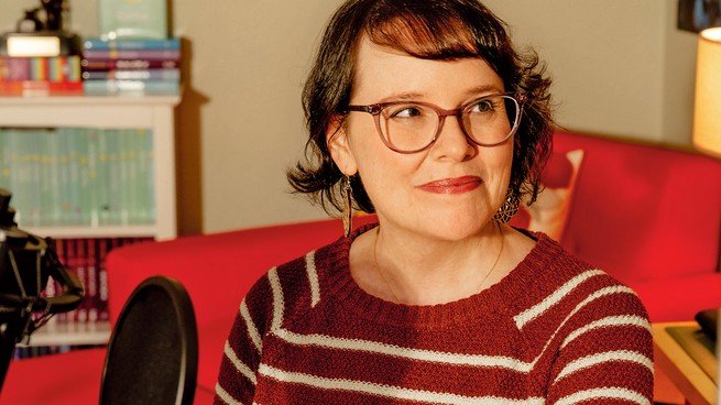 Photo of the cartoonist Raina Telgemeier smiling while sitting at a desk