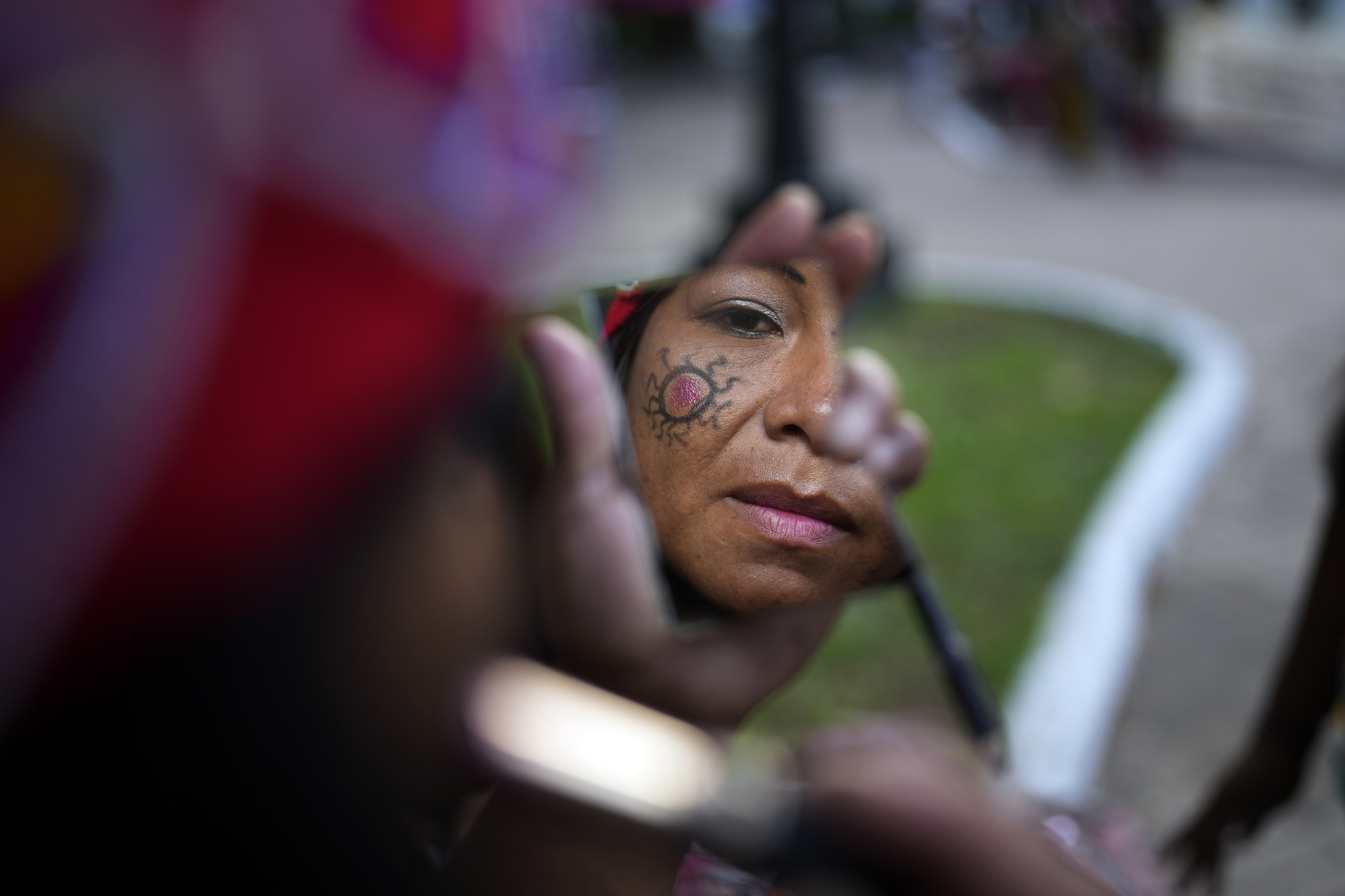 A Maka Indigenous woman puts on make-up before protesting for the recovery of ancestral lands in Asuncion, Paraguay, Wednesday, Feb. 28, 2024. Leader Mateo Martinez has denounced that the Paraguayan state has built a bridge on their land in El Chaco's Bartolome de las Casas, Presidente Hayes department. (AP Photo/Jorge Saenz)
