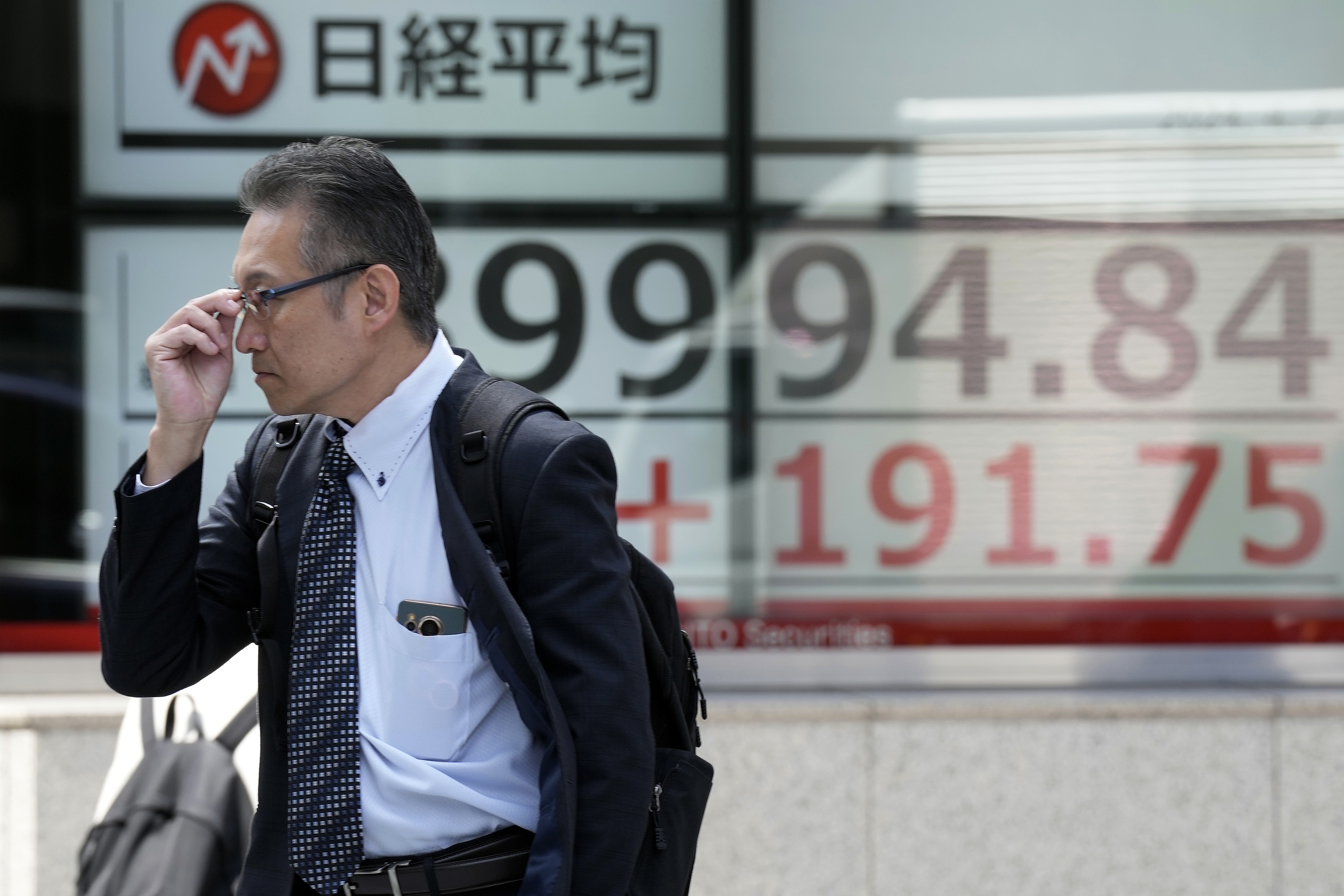A person walks in front of an electronic stock board showing Japan's Nikkei 225 index at a securities firm Tuesday, April 2, 2024, in Tokyo. Asian shares were mixed on Tuesday after Wall Street pulled back from its record following a shaky day of trading, putting at least a temporary halt to its huge rally since Halloween. (AP Photo/Eugene Hoshiko)
