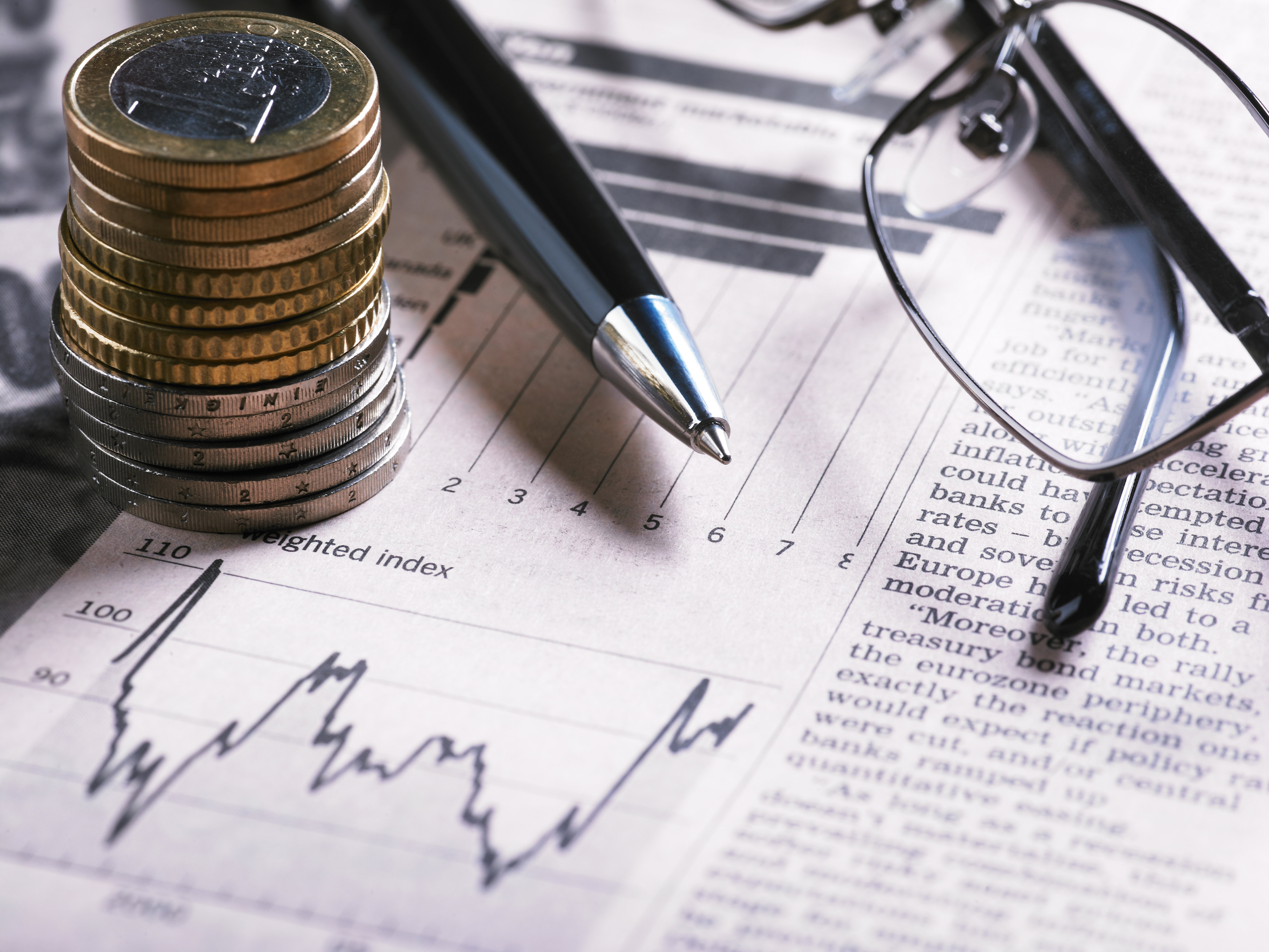 A financial chart with coins, glasses and pen