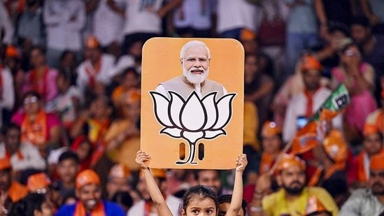 Stock market after Lok Sabha elections: A child holds a placard depicting PM Modi and BJP election symbol during a public meeting addressed by Uttar Pradesh Chief Minister Yogi Adityanath for Lok Sabha polls, in Varanasi.(PTI)