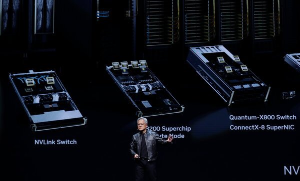 Jensen Huang on a stage with enlarged pictures of computer chips behind him.