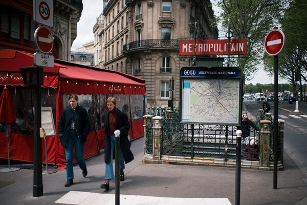 People walking near a restaurant with a red tent and a subway sign that says Metropolitan. 