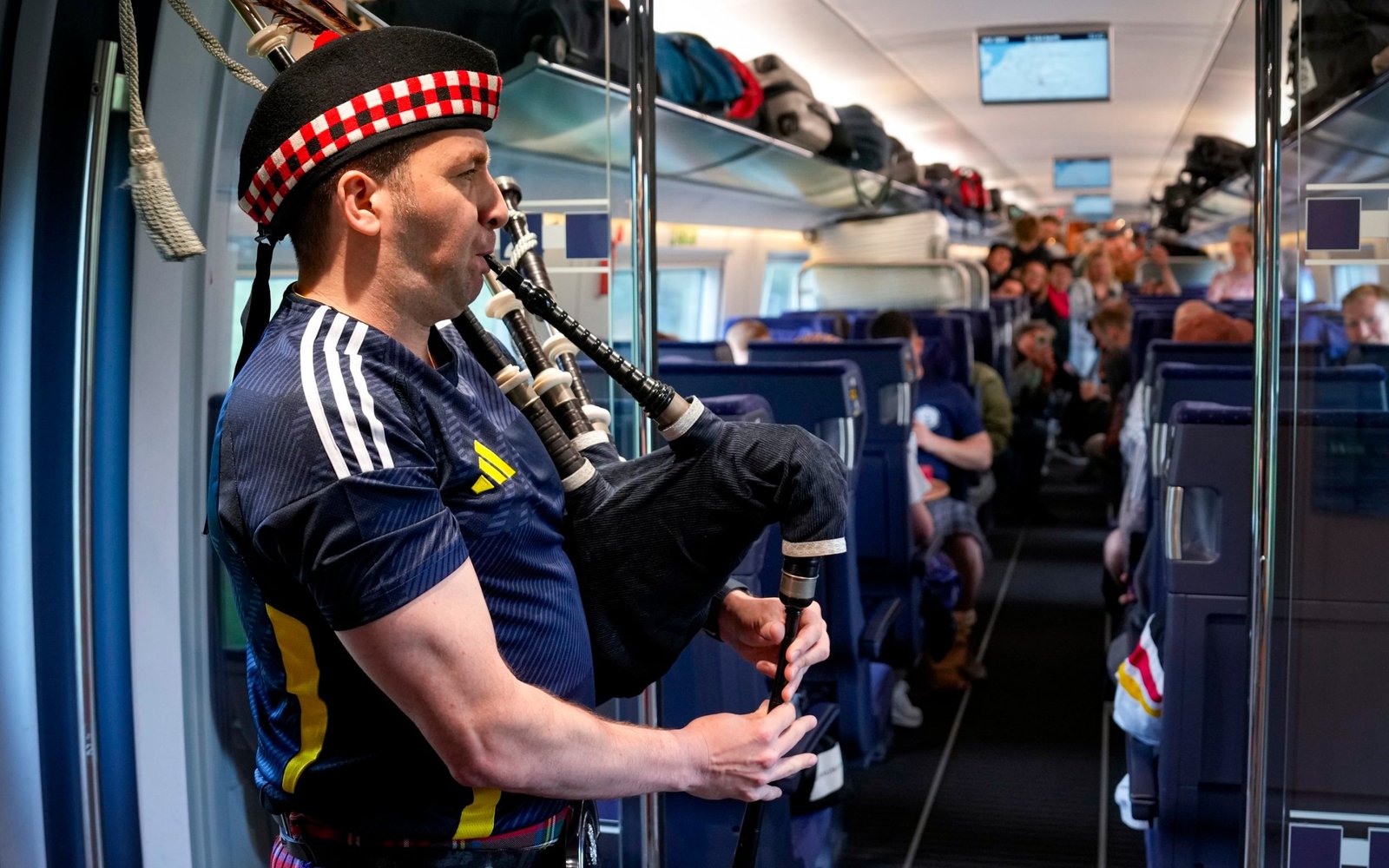 A Scotland fan serenades train passengers with his bagpipe 