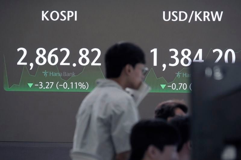 A currency trader watches monitors near the screen showing the Korea Composite Stock Price Index (KOSPI), top left, and the foreign exchange rate between U.S. dollar and South Korean won at the foreign exchange dealing room of the KEB Hana Bank headquarters in Seoul, South Korea, Wednesday, July 17, 2024. (AP Photo/Ahn Young-joon)
