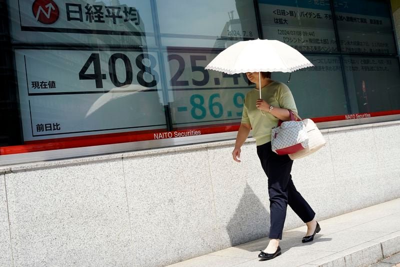 A person walks in front of an electronic stock board showing Japan's Nikkei 225 index at a securities firm under the intense sun Monday, July 8, 2024, in Tokyo. (AP Photo/Eugene Hoshiko)