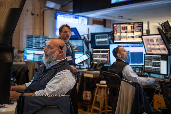 People sitting at desks with monitors at the New York Stock Exchange. 