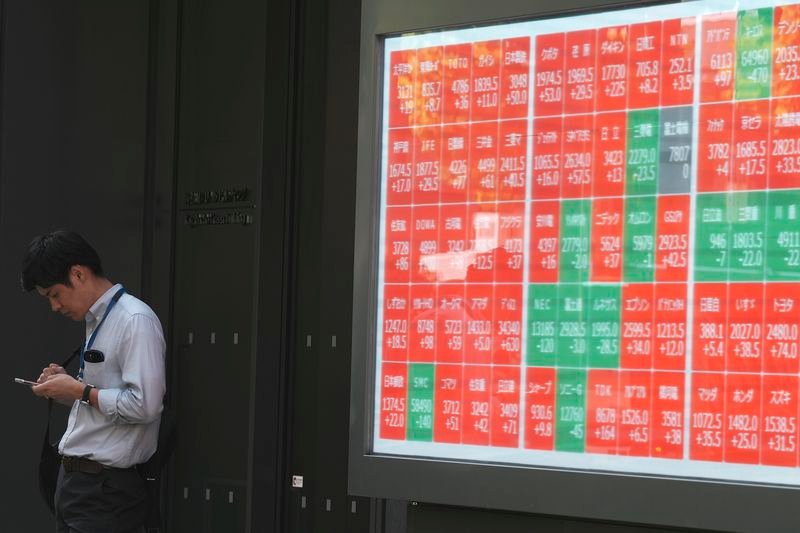 A person stands near an electronic stock board showing Japan's Nikkei index at a securities firm Wednesday, Sept. 18, 2024, in Tokyo. (AP Photo/Eugene Hoshiko)