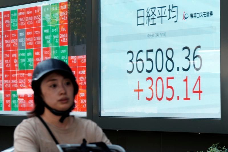 A person rides a bicycle in front of an electronic stock board showing Japan's Nikkei index at a securities firm Wednesday, Sept. 18, 2024, in Tokyo. (AP Photo/Eugene Hoshiko)