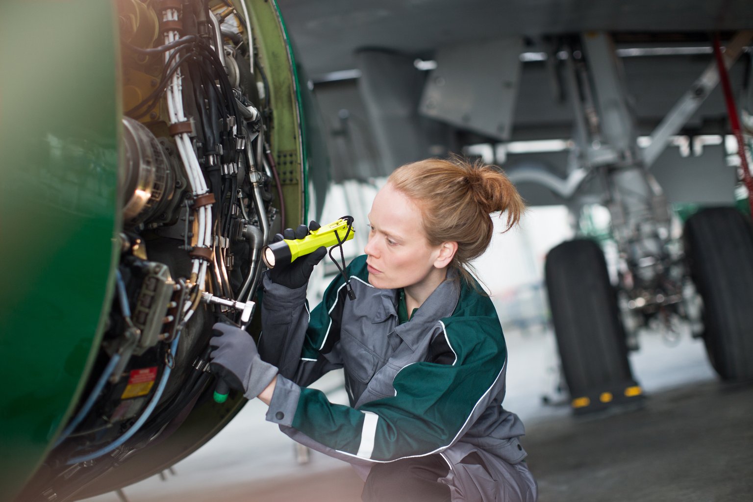 Engineer using flashlight to analyze airplane part