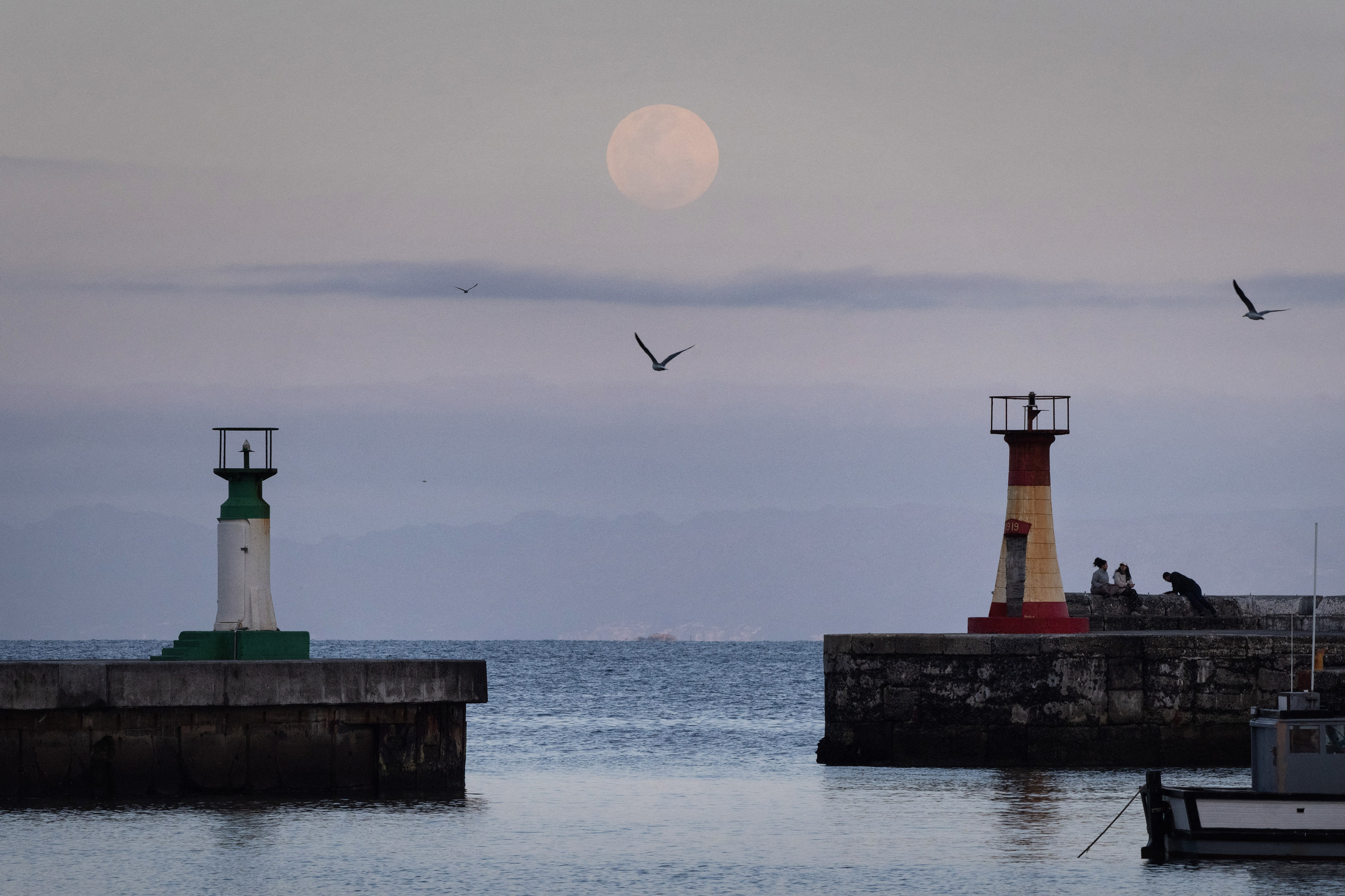 TOPSHOT - A full moon, this one also called The Harvest Moon, and one of 4 supermoons this year, rises over Kalk Bay Harbour, near Cape Town, on September 17, 2024. Supermoons happen when the moon is closest to earth, and appear bigger than usual. (Photo by RODGER BOSCH / AFP) (Photo by RODGER BOSCH/AFP via Getty Images)