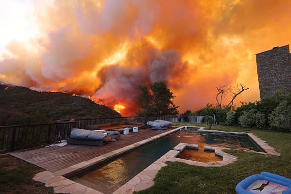 A brush fire burns near homes in Pacific Palisafes, California on Jan. 7, 2025.