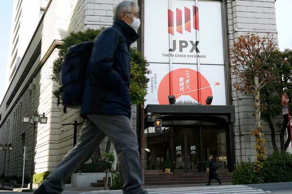 A person walks on the street in front of a building that reads 