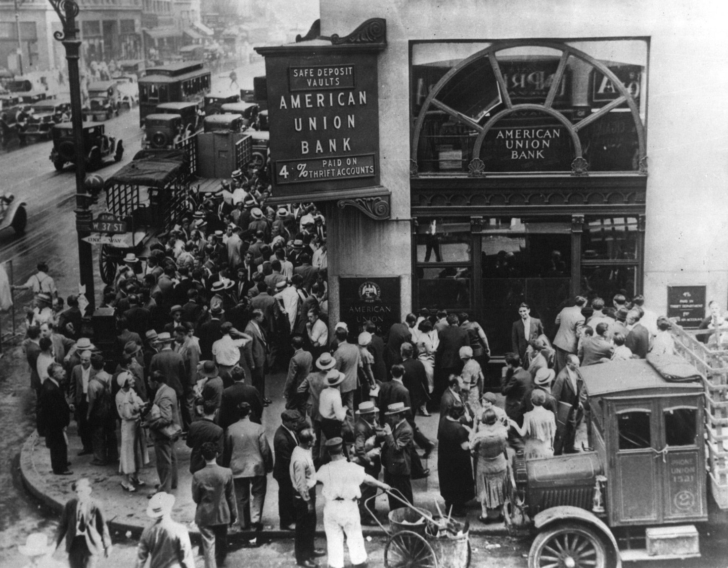A large crowd of people gathers outside the American Union Bank in a 1930s city street scene. The bank’s entrance and a vintage delivery truck are visible. The crowd appears to be anxiously waiting or protesting, capturing a moment of financial history.