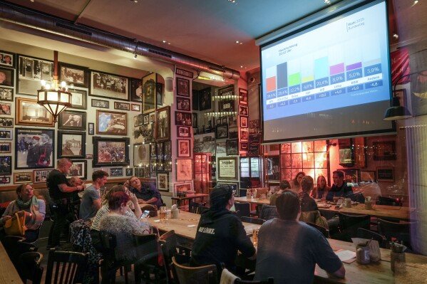 People watch first prjections at a pub in Berlin, Germany, Sunday, Feb. 23, 2025, after the German national election. (AP Photo/Martin Meissner)
