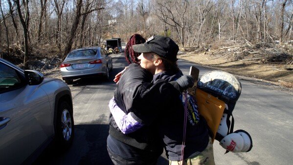 In this photo, made from video taken on Friday, Feb. 7, 2025, in Swannanoa, N.C., Angie McGee, left, hugs Jill Holtz as she prepares to go home with some cherished mementos she thought she'd lost forever. (AP Photo/Allen G. Breed)