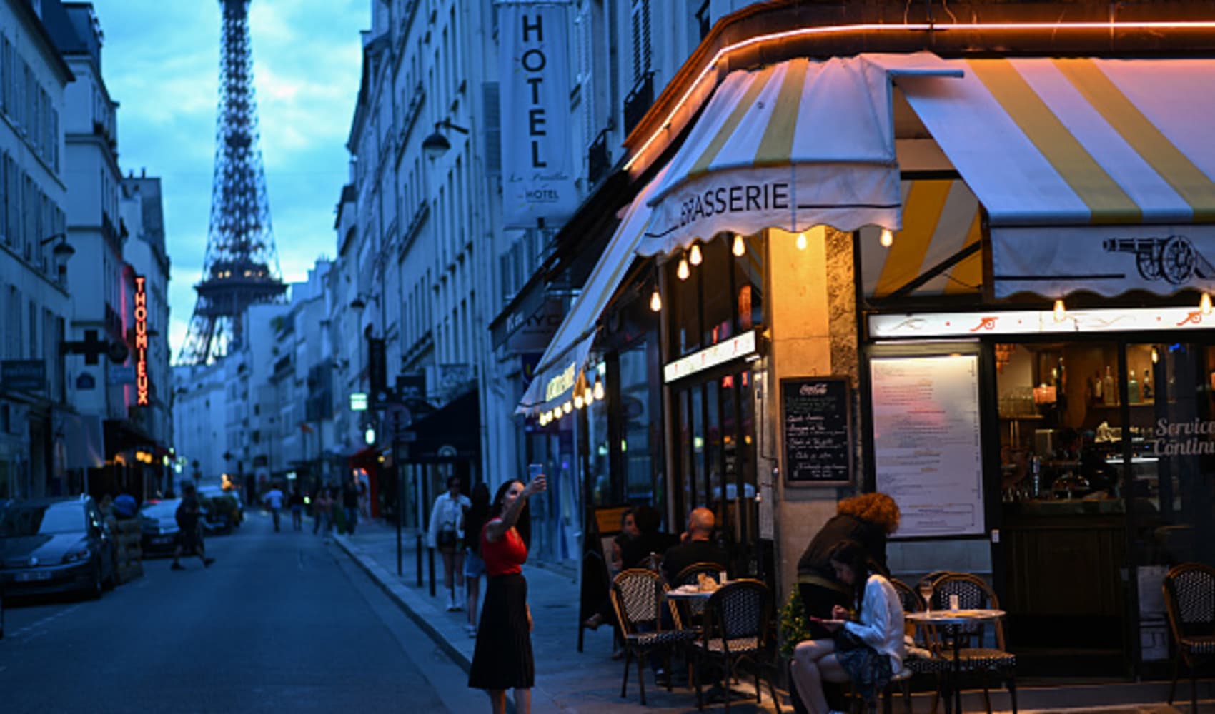 A woman takes a selfie photo, with the Eiffel Tower in the background, at Surcouf street in Paris, on July 23, 2024, ahead of the Paris 2024 Olympic Games. 