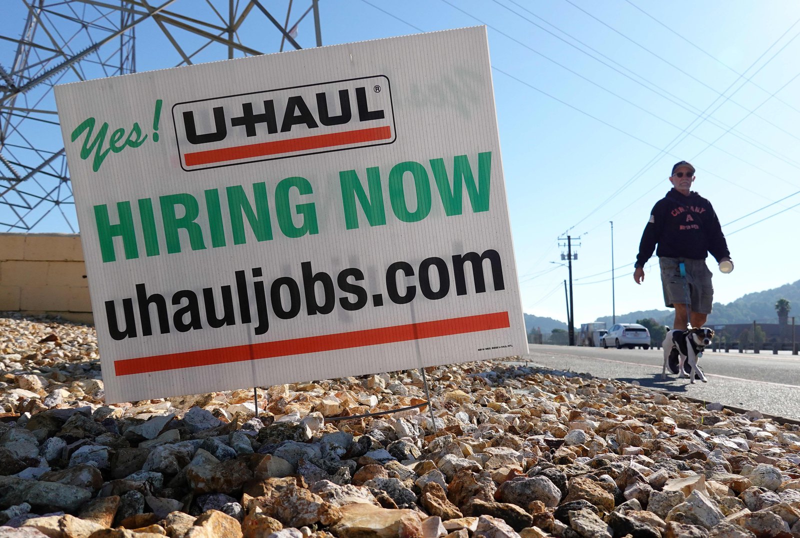 A pedestrian walks by a 'hiring now' sign in front of a U-Haul store on December 03, 2024 in San Rafael, California. 