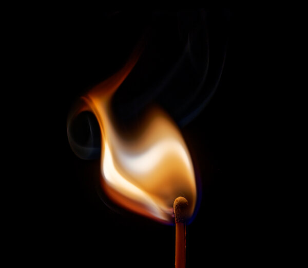 A photograph of a lit match, its bright flame contrasting against a black background.