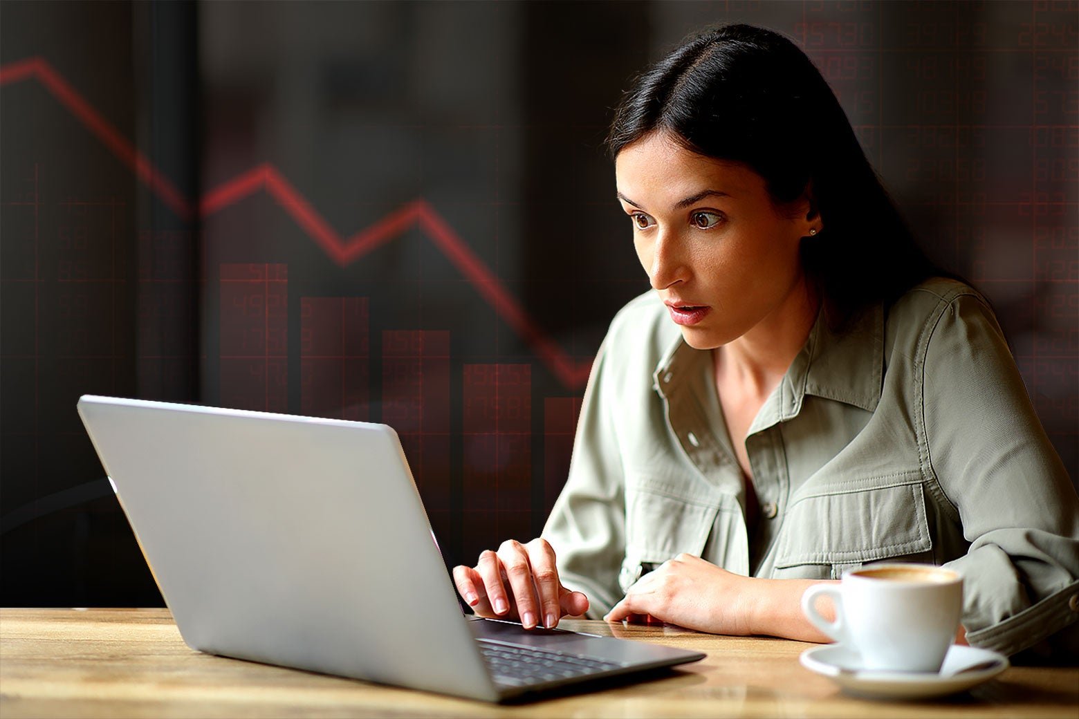 A woman looks astonished at her laptop against the backdrop of a chart depicting a plummeting stock value.