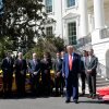 In this photo, President Trump stands outside the White House with a yellow race car and several race car drivers and team owners.