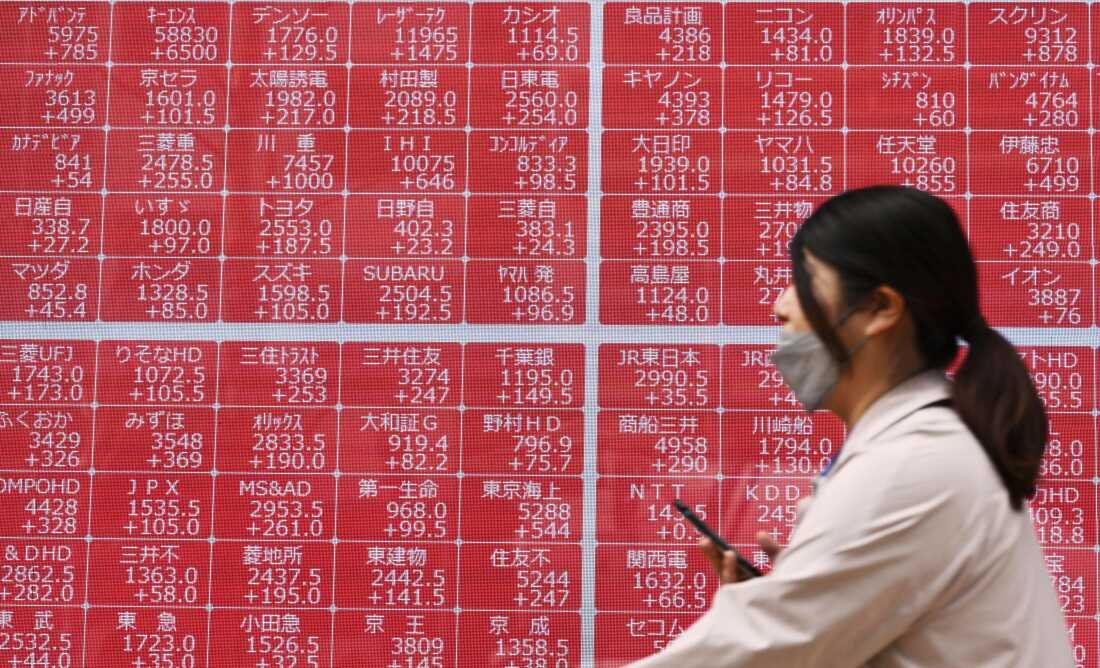 A person walks past an electronic stock board at a securities firm in Tokyo Thursday, April 10, 2025.