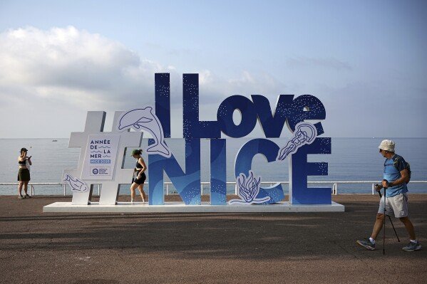 People walk on the sea promenade ahead of the U.N. Ocean Conference, Saturday, June 7, 2025, in Nice, France. (AP Photo/Laurent Cipriani)