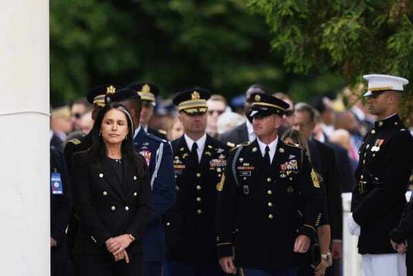 Director of National Intelligence Tulsi Gabbard, left, looks on before President Donald Trump arrives to deliver a Memorial Day Address at the 157th National Memorial Day Observance at Arlington National Cemetery, Monday, May 26, 2025, in Arlington, Va. (AP Photo/Julia Demaree Nikhinson)