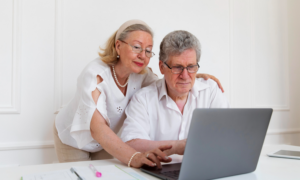 A senior-age man and woman check their financial accounts on a laptop