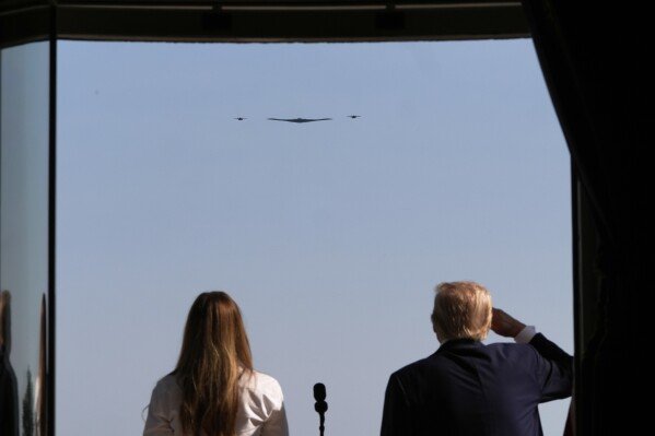 President Donald Trump, right, and first lady Melania Trump observe as B-2 Spirit stealth bombers perform a military flyover from the Blue Room balcony of the White House during a Fourth of July celebration in Washington, Friday, July 4, 2025. (AP Photo/Alex Brandon, Pool)