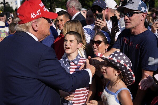 President Donald Trump, left, greets active-duty military service members and their families during a Fourth of July celebration on the South Lawn of the White House in Washington, Friday, July 4, 2025. (AP Photo/Alex Brandon, Pool)