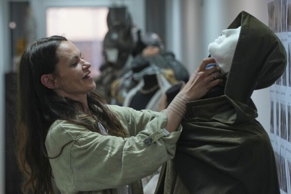 A costume designer prepares a costume for actor Jack Patten as Robin, on set of the series Robin Hood, in Belgrade, Serbia, Monday, May 5, 2025. (AP Photo/Darko Vojinovic)