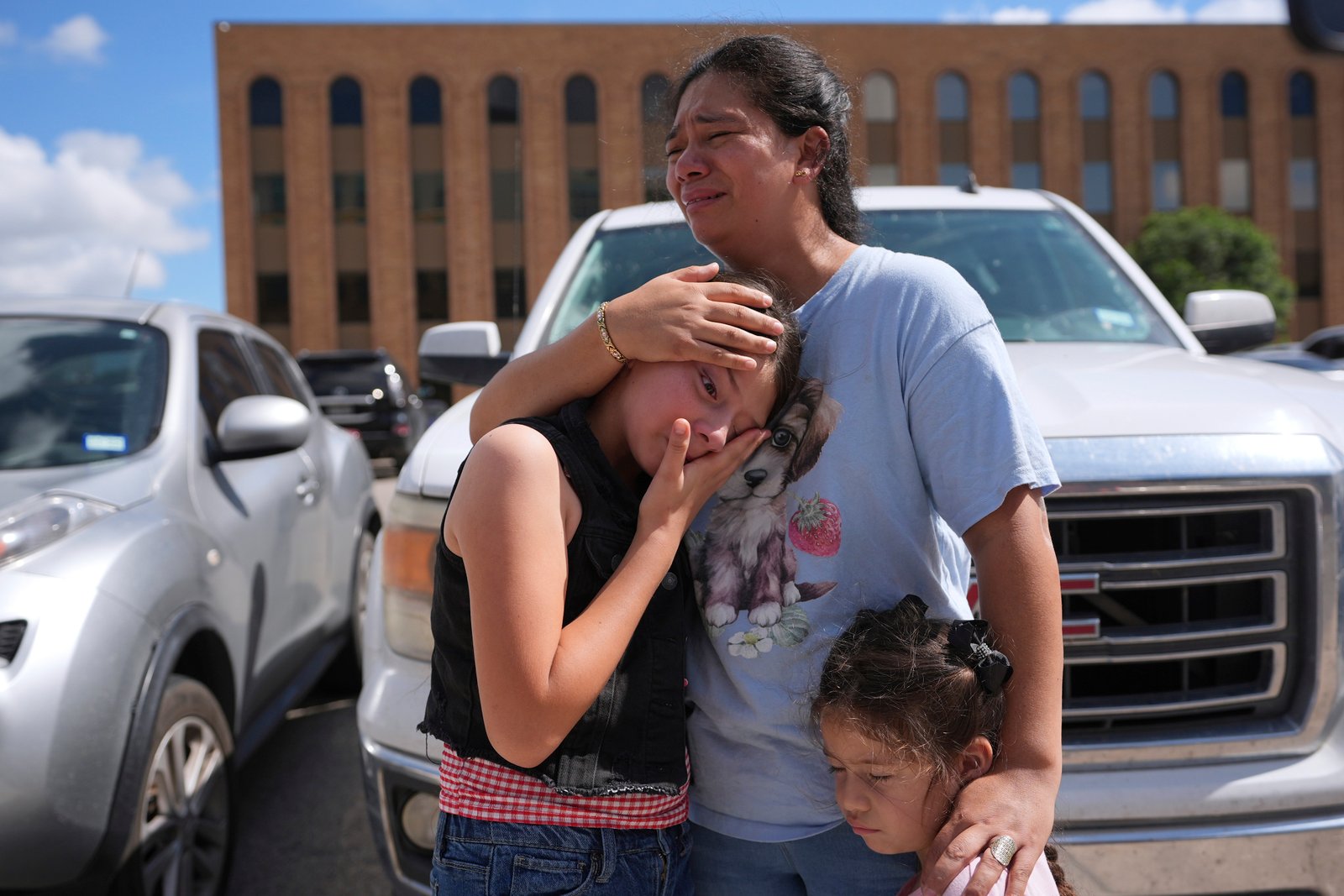Narel Lopez comforts her daughters after her husband and a son were detained and taken away in a bus following an appearance at immigration court, Wednesday, June 25, 2025, in San Antonio, Texas. (AP Photo/Eric Gay)