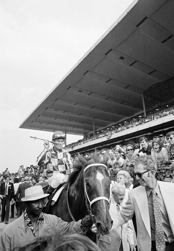 Groom Eddie Sweat, left, leads Secretariat, carrying jockey Ron Turcotte, off the track after winning the Belmont Stakes and the Triple Crown at Belmont Park in Elmont, N.Y., June 9, 1973. Secretariat's owner, Penny Chenery, second from right and behind, and his trainer, Lucien Laurin, second from right and front, walk alongside him. (AP Photo)