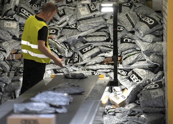 A staff member unloads a container at the DHL Mega Parcel Center in Ludwigsfelde near Berlin, Germany, May 31, 2022. (AP Photo/Michael Sohn, File)