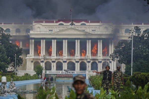 Nepalese army soldiers disperse protesters from Singha Durbar, the seat of Nepal's government's various ministries and offices, after it was set on fire during a protest against a social media ban and corruption in Kathmandu, Nepal, Tuesday, Sept. 9, 2025. (AP Photo/Niranjan Shrestha)