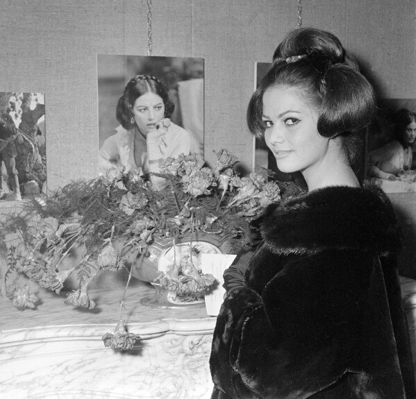 Italian actress Claudia Cardinale stands in front of a picture of herself as she appears in the film 