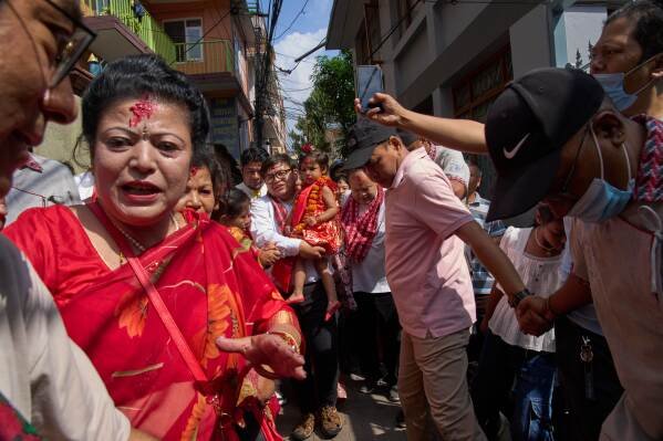 Nepal's newly appointed living goddess, Kumari Aryatara Shakya, is carried by her family member as they get ready to walk towards Kumari Ghar, the temple palace where she will be residing in Kathmandu, Nepal, Tuesday, Sept. 30, 2025. (AP Photo/Niranjan Shrestha)