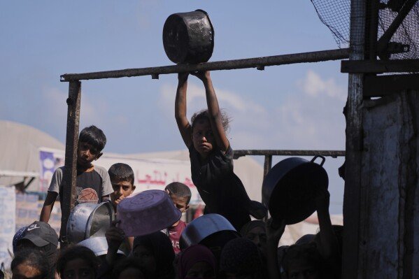 FILE - Palestinian children gather to receive donated food at a community kitchen in Khan Younis, southern Gaza Strip, Sept. 19, 2025. (AP Photo/Jehad Alshrafi, File)