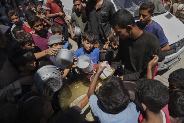 FILE - Palestinian children receive donated food at a community kitchen in Deir al-Balah, in the central Gaza Strip, Sept. 12, 2025. (AP Photo/Abdel Kareem Hana)