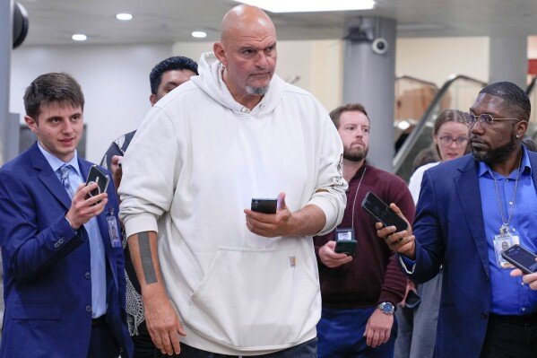 Sen. John Fetterman, D-Pa., center, speaks with reporters at the Capitol subway, Sept. 17, 2025, in Washington. (AP Photo/Mariam Zuhaib, File)