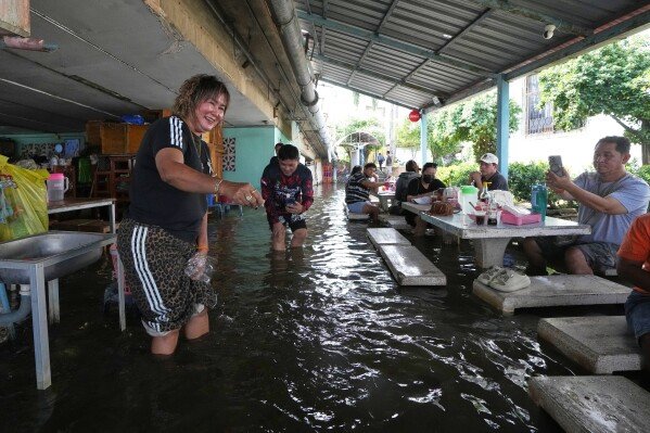 Diners at the Pa Jit restaurant take vdo fish in the aisles that come from floods from the Tha Chin River in Thailand's Nakhon Pathom province, west of Bangkok, Thailand, Friday, Nov. 14, 2025. (AP Photo/Sakchai Lalit)