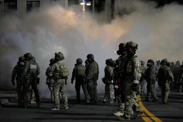 Law enforcement officers stand in tear gas outside a U.S. Immigration and Customs Enforcement facility during a protest Oct. 4, 2025, in Portland, Ore. (AP Photo/Jenny Kane, File)