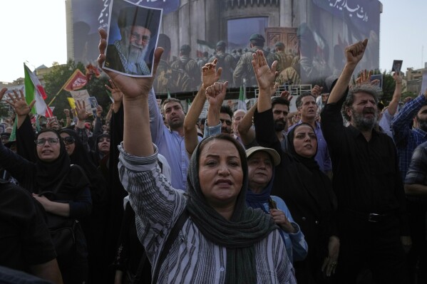 Protesters chant slogans as one of them holds up a poster of the Iranian Supreme Leader Ayatollah Ali Khamenei in a protest following the U.S. attacks on nuclear sites in Iran, in Tehran, Iran, Sunday, June 22, 2025. (AP Photo/Vahid Salemi)