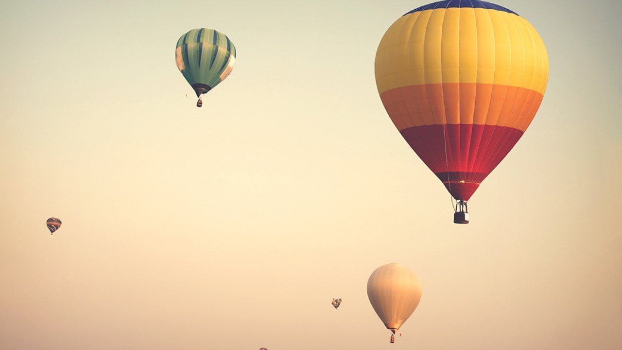 Hot air balloons up on a cloudy sky.