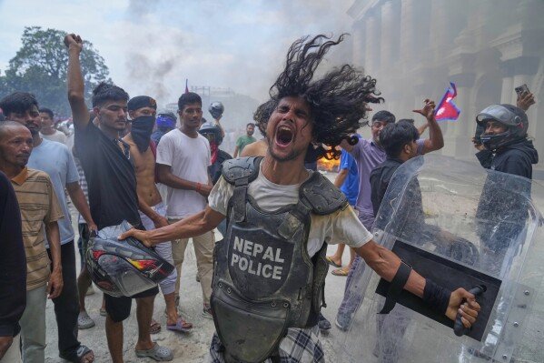 A protester, wearing a flak jacket and carrying a shield snatched from a policeman, shouts outside the Singha Durbar, the seat of Nepal's government, during a protest against corruption and a ban on social media in Kathmandu, on Sept. 9, 2025. (AP Photo/Niranjan Shrestha)