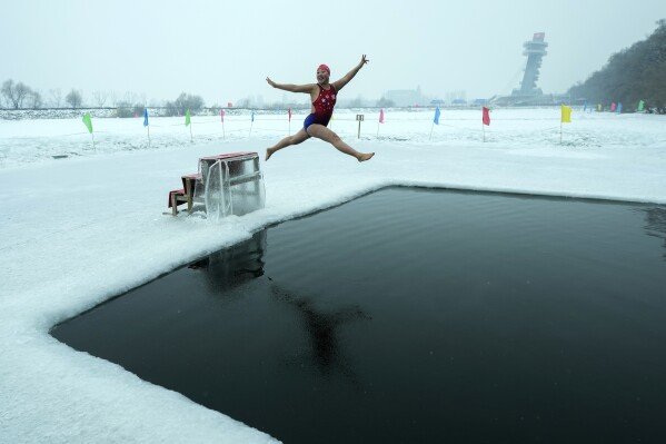 Yu Xiaofeng leaps into a pool carved from ice on the frozen Songhua River in Harbin, China, on Jan. 7, 2025. (AP Photo/Andy Wong)