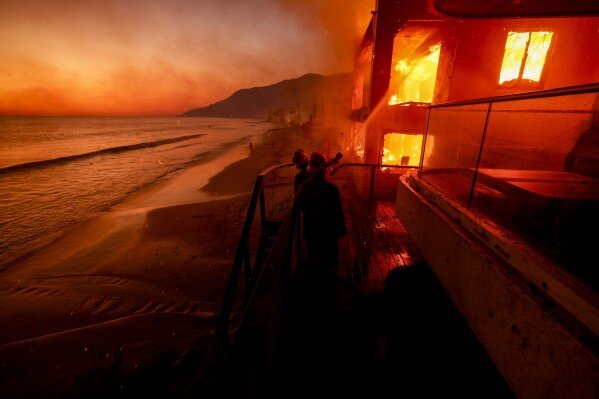 Firefighters battle flames engulfing a beachfront property in Malibu, Calif., during the Palisades Fire on Jan. 8, 2025. (AP Photo/Etienne Laurent)