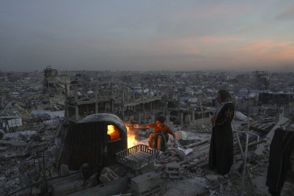 Palestinians Ali Marouf and his mother, Aisha, cook on the roof of their house, which was destroyed by an Israeli offensive, in Jabaliya, Gaza Strip, on March 17, 2025. (AP Photo/Jehad Alshrafi)