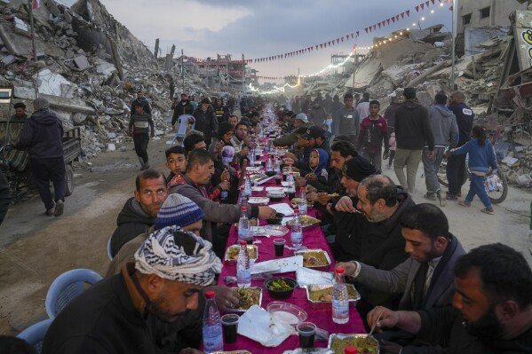 Palestinians gather at a table, surrounded by the rubble of destroyed homes and buildings, for iftar, the fast-breaking meal, on the first day of Ramadan in Rafah, southern Gaza Strip, March 1, 2025. (AP Photo/Abdel Kareem Hana)